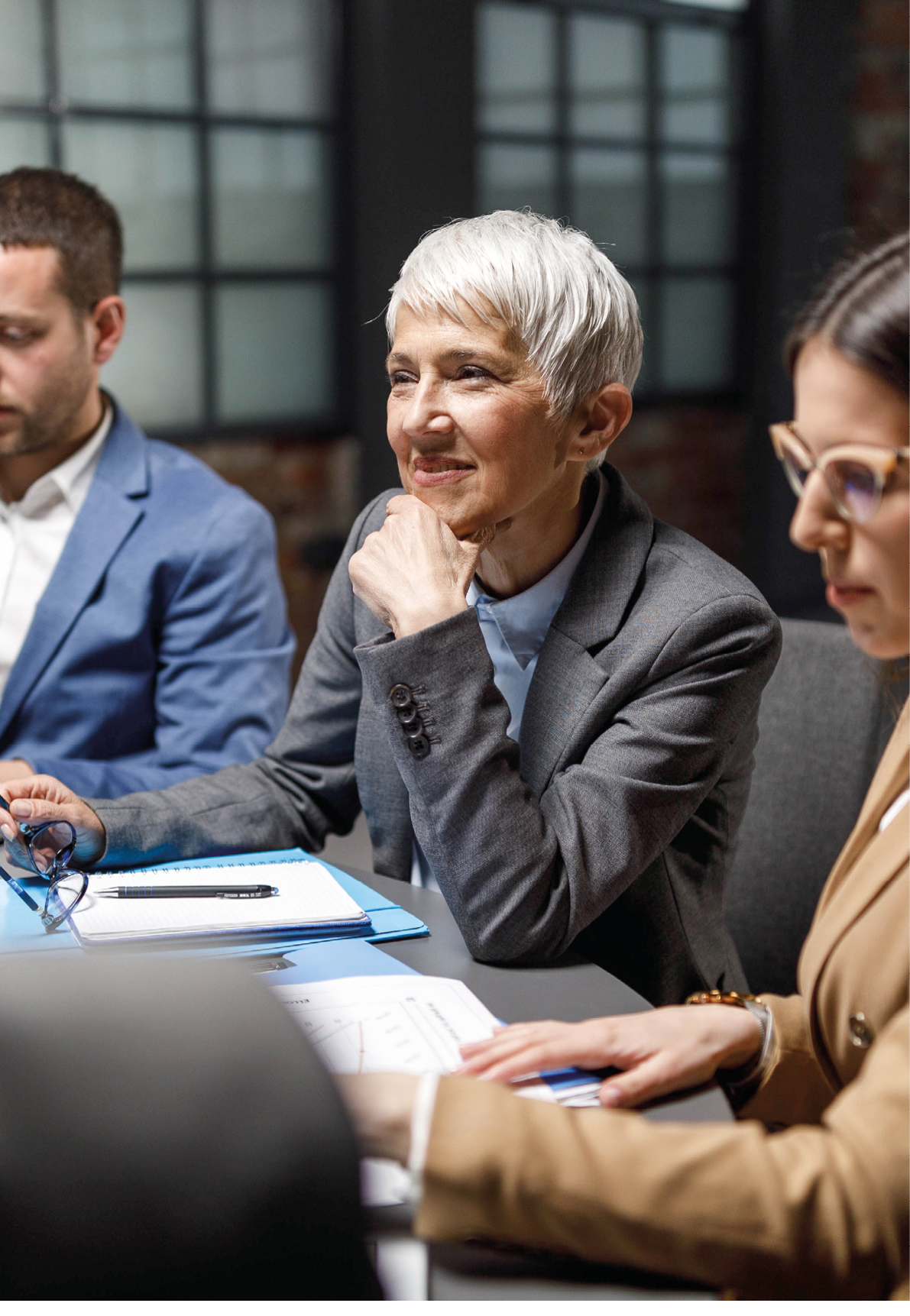 Happy senior entrepreneur listening to her colleagues during a meeting in the office.